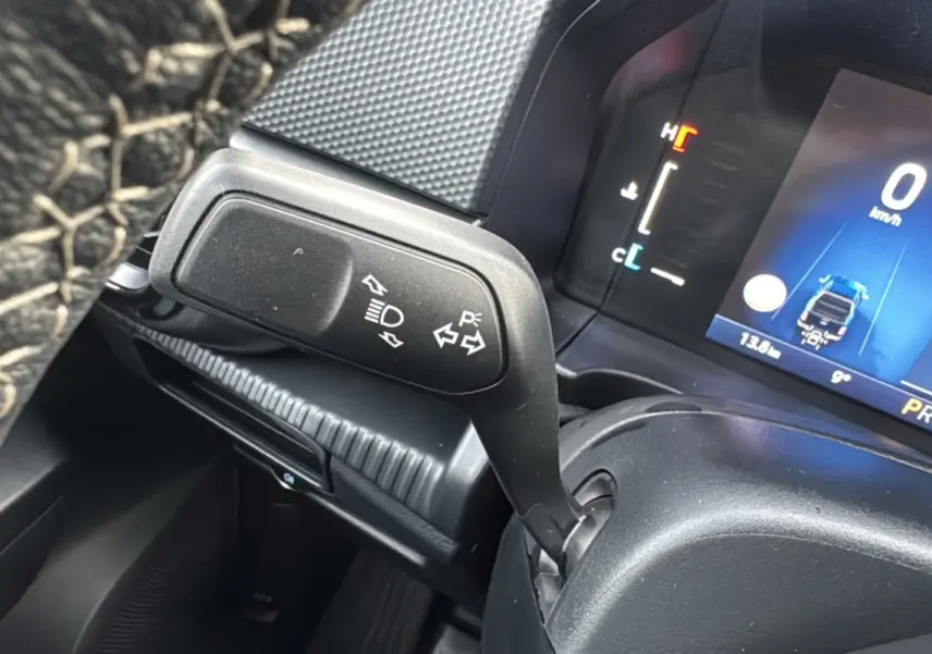 Gros plan sur la manette de clignotant et le tableau de bord numérique du Ford Ranger blanc glacier 2025.