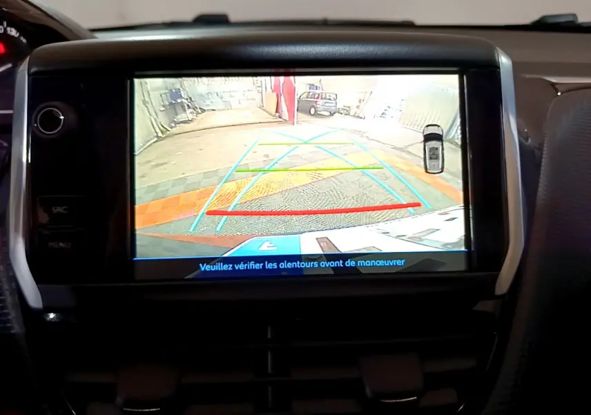 Écran tactile intérieur affichant la caméra de recul du Peugeot 2008 gris foncé avec lignes de guidage colorées.