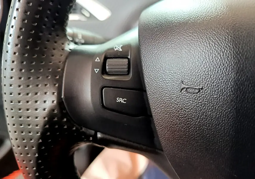 Gros plan sur le volant cuir perforé du Peugeot 2008 2019, avec commandes audio intégrées visibles.