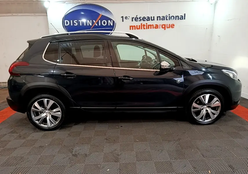 Peugeot 2008 gris foncé vue de profil côté gauche, avec jantes alliage et barres de toit chromées visibles