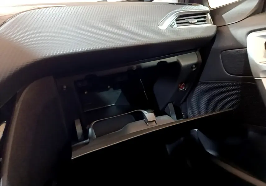 Intérieur du Peugeot 2008 gris foncé, vue côté passager sur la boîte à gants ouverte et tableau de bord texturé.