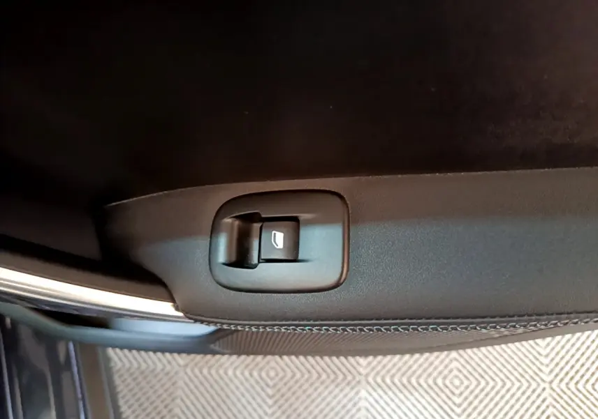 Bouton de commande de vitre électrique sur la porte intérieure d'une Peugeot 2008 gris foncé, vue rapprochée.
