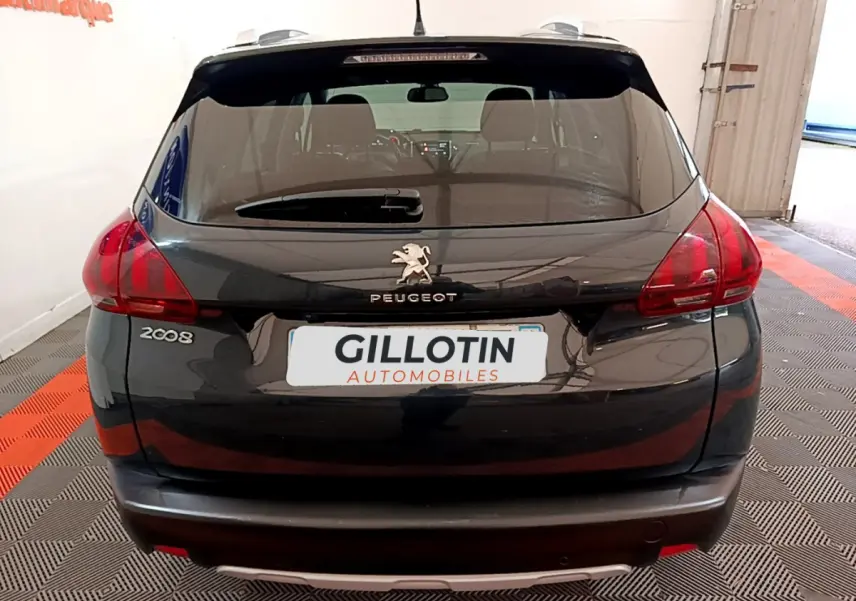 Vue arrière d'un Peugeot 2008 gris foncé avec feux rouges et logo lion sur le hayon dans un garage.