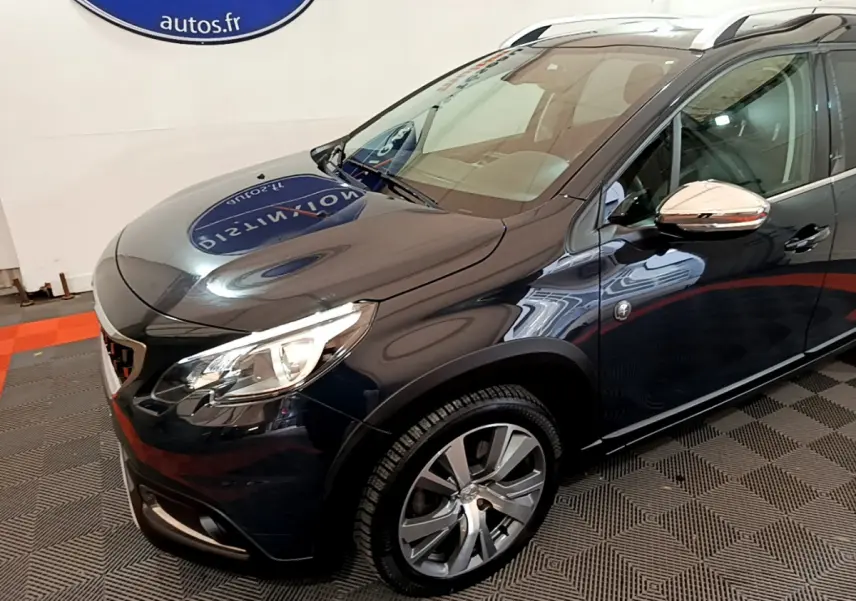 Vue 3/4 avant droit d'un Peugeot 2008 gris foncé avec jantes alliage et rétroviseurs chromés.