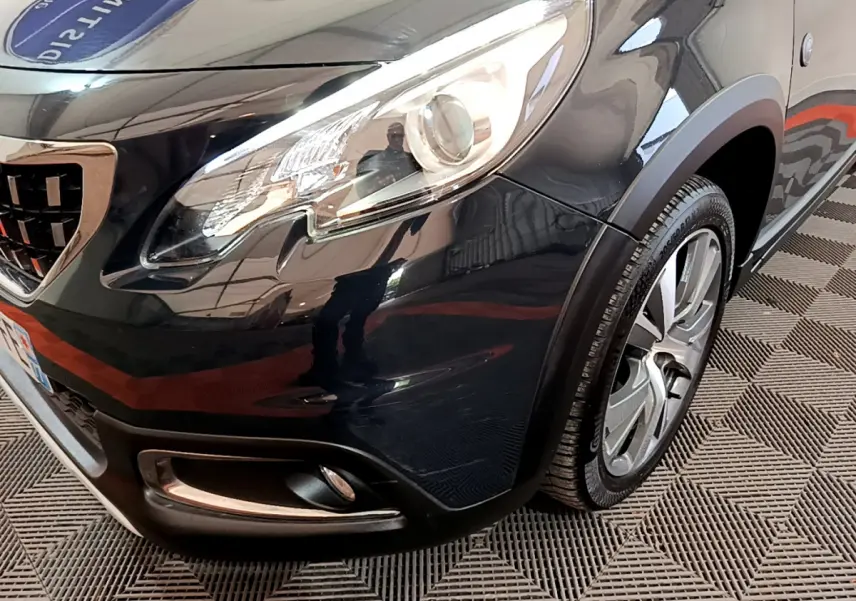 Gros plan sur l'avant droit gris foncé du Peugeot 2008 2019 avec phare et jante alliage visible.