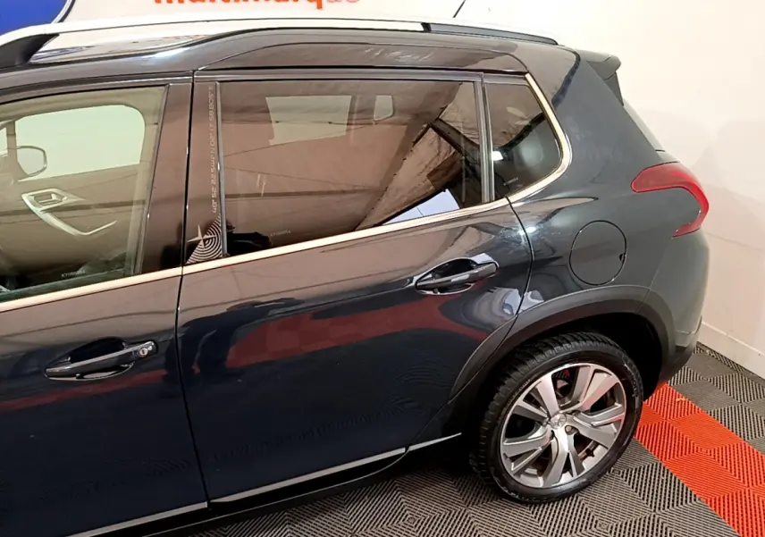 Vue latérale côté droit du Peugeot 2008 gris foncé avec poignées de porte et jante arrière visibles.