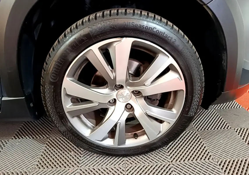 Gros plan sur la roue avant gauche avec jante alliage argentée du Peugeot 2008 gris foncé 2019 Crossway