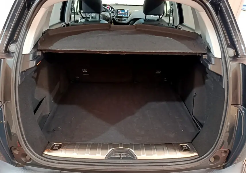 Coffre ouvert d’un Peugeot 2008 gris foncé, vue arrière montrant l’espace de chargement et l’intérieur avant avec écran tactile.