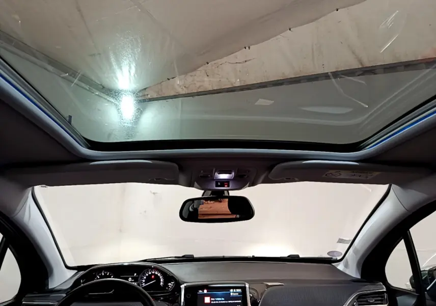 Vue intérieure avant du Peugeot 2008 gris foncé 2019, avec toit panoramique et tableau de bord tactile allumé.