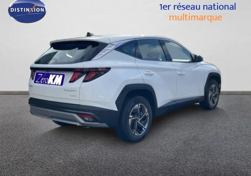 Vue 3/4 arrière droite d'un Hyundai Tucson blanc Atlas avec jantes bi-ton et feux arrière LED distinctifs.