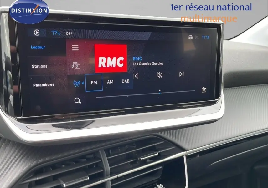 Écran tactile central affichant la radio RMC dans l'habitacle noir du Peugeot 208 1.2 PureTech 2024.
