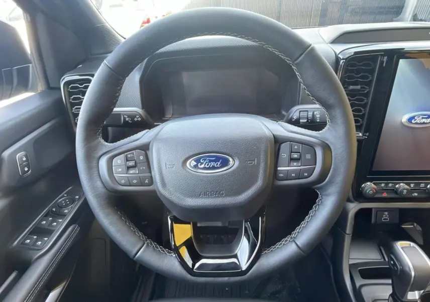 Vue centrée sur le volant cuir multifonctions du Ford Ranger 2025, avec écran tactile et commandes au volant visibles.