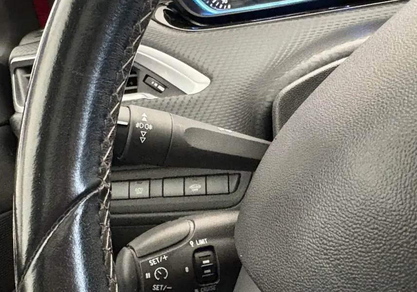 Gros plan sur le volant cuir et commandes de régulateur de vitesse du Peugeot 2008 rouge Puretech 2019