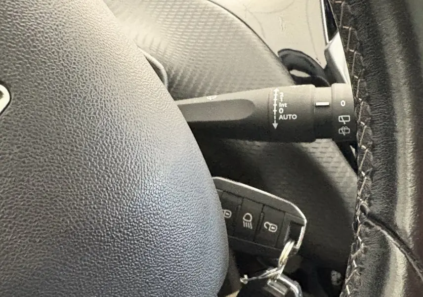 Gros plan sur le volant cuir noir et la commande d’essuie-glace du Peugeot 2008 Puretech 110 rouge de 2019.