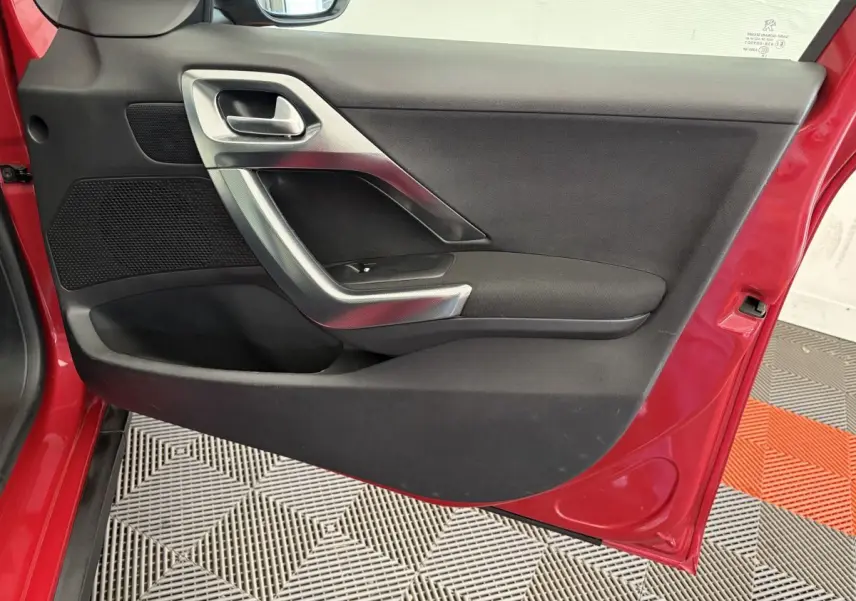 Vue rapprochée de la porte avant gauche rouge d'un Peugeot 2008 2019, avec poignée argentée et panneau noir.