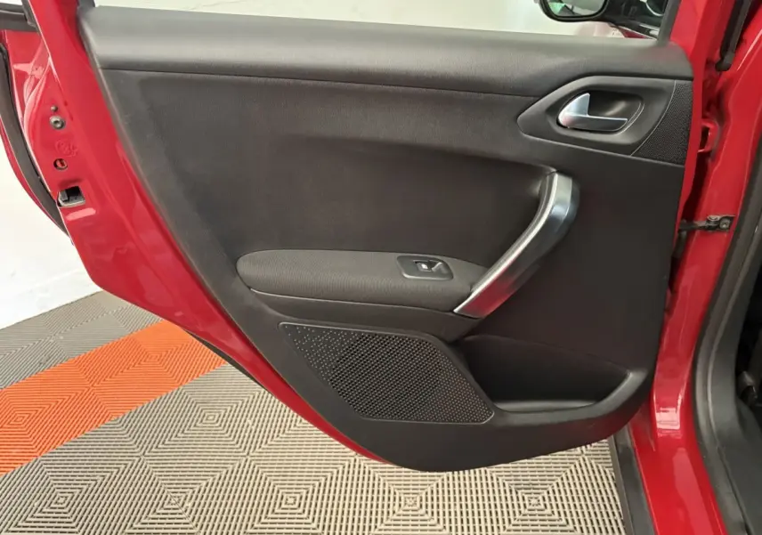 Vue rapprochée de la porte arrière gauche rouge du Peugeot 2008 avec poignée argentée et panneau noir intérieur.