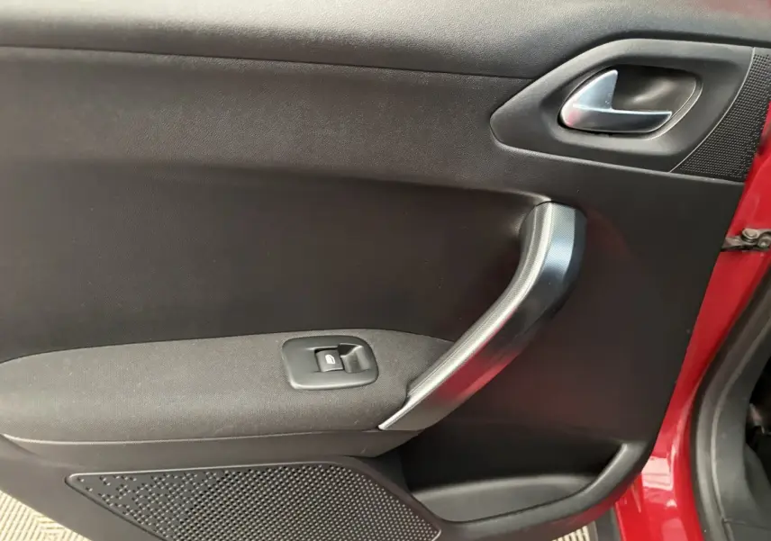 Vue rapprochée de la porte côté gauche rouge d'un Peugeot 2008 2019 avec poignée argentée et bouton de lève-vitre.