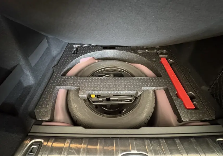 Roue de secours et kit de réparation logés sous le plancher du coffre du Peugeot 2008 rouge, vue intérieure du coffre.