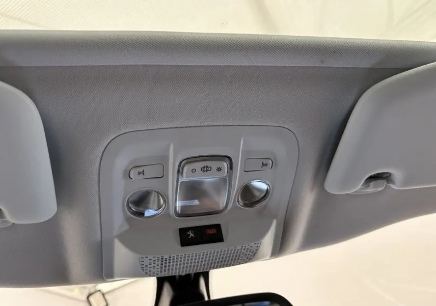 Plafonnier intérieur gris clair avec commandes d'éclairage et bouton SOS dans un Peugeot 2008 rouge, vue de dessous