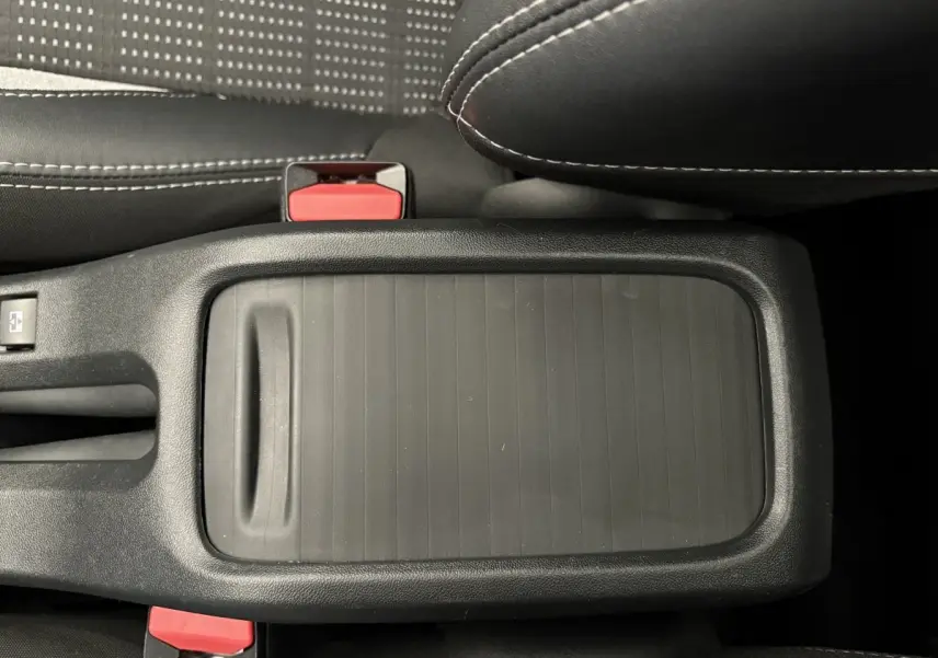 Vue rapprochée du rangement central noir entre les sièges avant d’un Peugeot 2008 rouge modèle 2019.