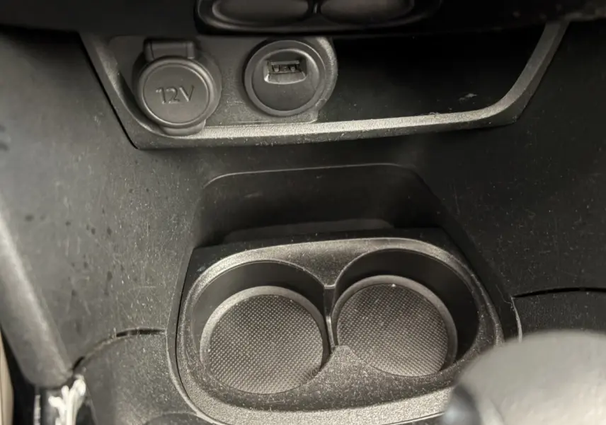 Prise 12V et port USB au-dessus des porte-gobelets noirs dans l'habitacle du Peugeot 2008 Puretech 2019.