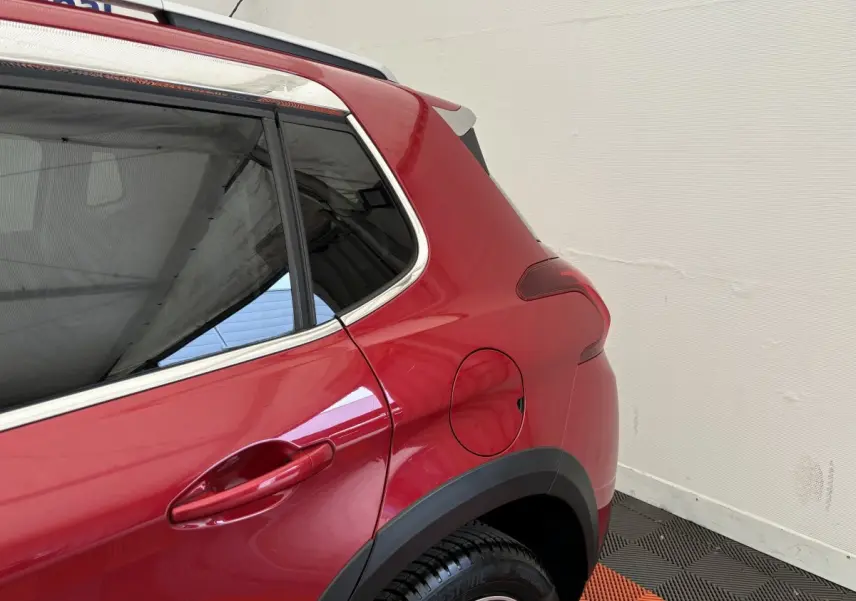 Vue rapprochée du côté arrière gauche d’un Peugeot 2008 rouge, mettant en valeur la porte et la trappe à carburant.