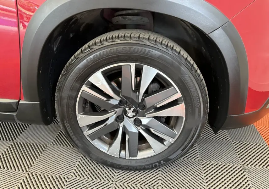 Gros plan sur la roue avant gauche d’un Peugeot 2008 rouge avec jante alliage et pneu Bridgestone.