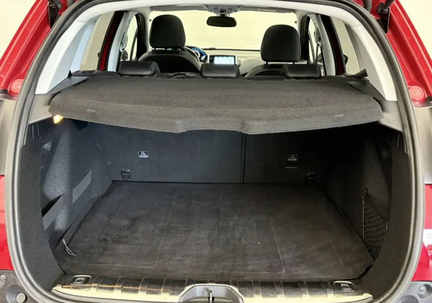 Coffre ouvert d'un Peugeot 2008 rouge vu de l'arrière, avec tablette cache-bagages et intérieur noir visible.