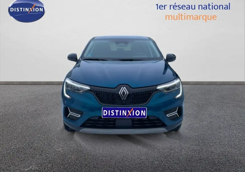 Vue frontale d'une Renault Arkana bleu Zanzibar métal avec calandre noire et feux LED allumés sur fond neutre.