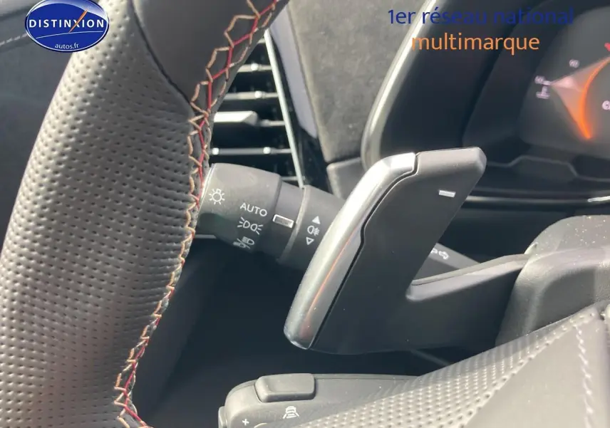 Gros plan sur la palette de changement de vitesses au volant de la DS7 Crystal pearl, intérieur noir avec surpiqûres rouges.