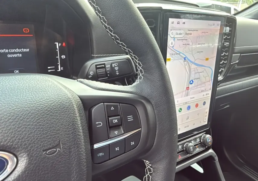 Vue intérieure du tableau de bord du Ford Ranger noir agate 2025, avec volant multifonctions et écran tactile vertical affichant la navigation.