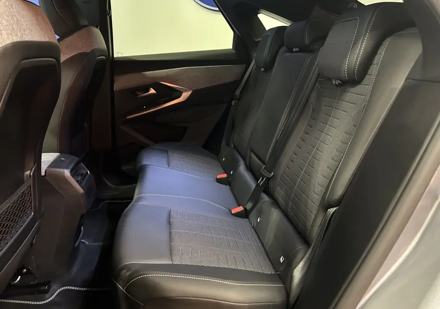 Vue latérale droite de l’arrière du Peugeot 3008 Hybrid gris Artense, montrant les sièges arrière en cuir noir avec surpiqûres blanches.