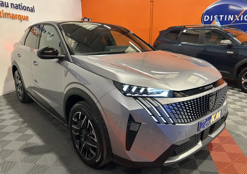 Peugeot 3008 gris Artense en 3/4 avant droit, avec calandre distinctive et feux LED allumés dans un showroom.