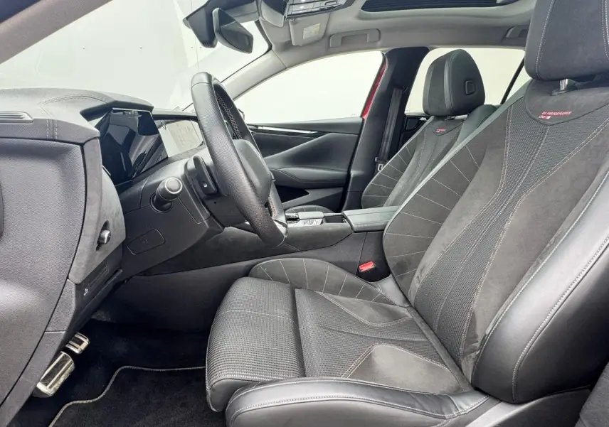 Intérieur avant droit de la DS4 2022, sièges cuir et Alcantara noirs avec surpiqûres rouges et toit panoramique visible.