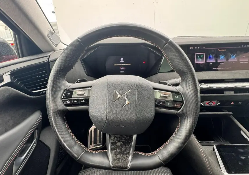 Vue rapprochée du volant en cuir noir avec surpiqûres rouges et tableau de bord numérique du DS4 Performance Line 2022.