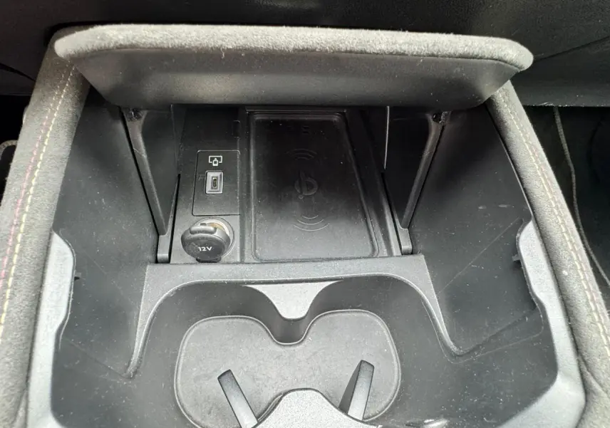 Gros plan sur la console centrale noire du DS4 II avec porte-gobelets, prise 12V et chargeur sans fil intégré.