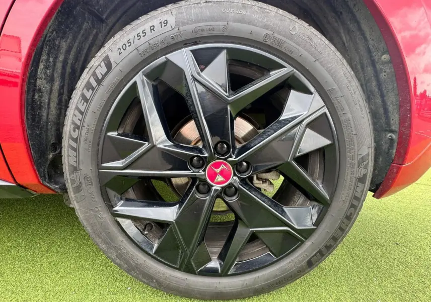 Gros plan sur la jante noire brillante 19 pouces avec logo DS rouge du DS4 rouge foncé, côté gauche avant.