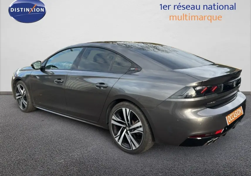 Vue 3/4 arrière droite d'une Peugeot 508 gris platinium, avec jantes bi-ton et feux arrière caractéristiques GT Line.