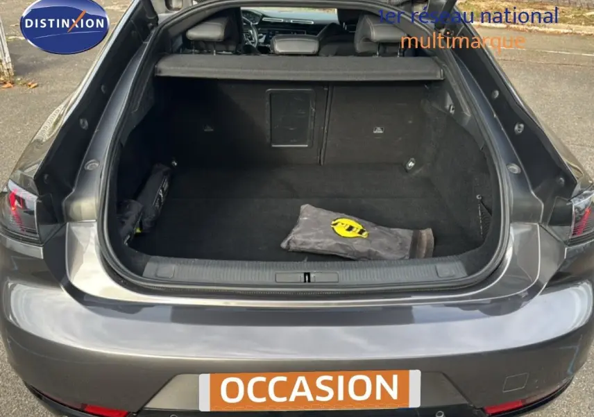 Vue arrière ouverte sur le coffre spacieux d'une Peugeot 508 gris platinium, avec attelage visible et intérieur noir.
