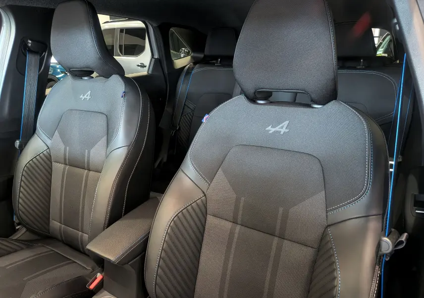 Gros plan sur les sièges avant noirs avec surpiqûres bleues et logo Alpine, intérieur du Renault Symbioz E-TECH 2026.