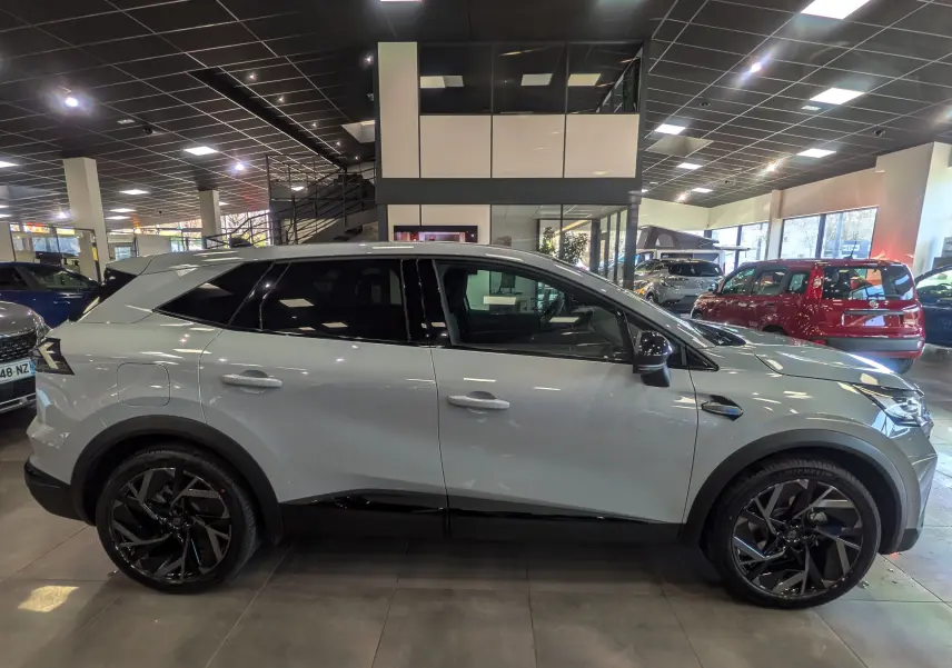 Vue de profil côté gauche du Renault SYMBIOZ E-TECH gris Rafale avec jantes noires et toit noir en concession.