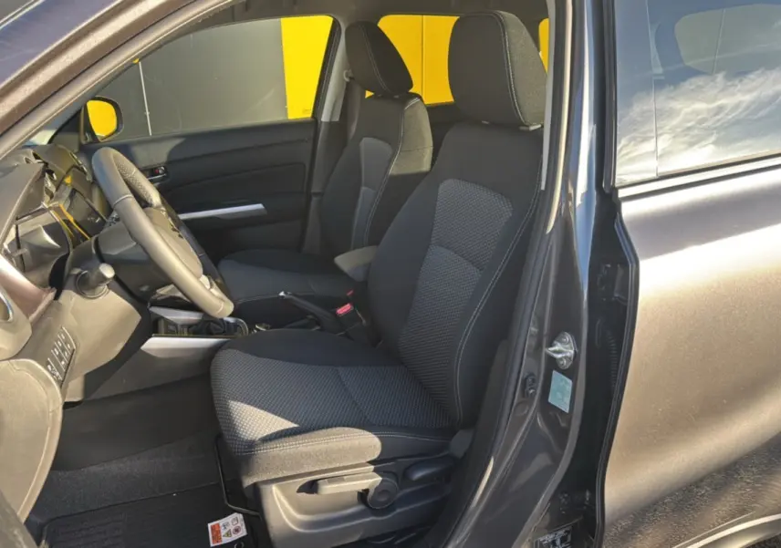 Intérieur avant droit du Suzuki Vitara Hybrid 110 Privilege AllGrip 2025 en Titan dark gray, sièges tissu gris et volant cuir.