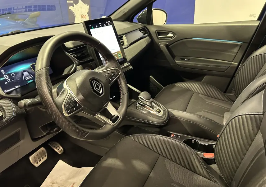 Vue intérieure côté conducteur du Renault Captur II Ph.2 avec volant multifonction, écran tactile vertical et sièges noirs.