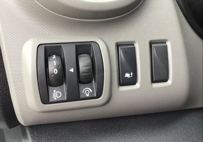 Gros plan sur les commandes d'éclairage et d'assistance au freinage du Renault Trafic Plancher Cabine blanc de 2019.