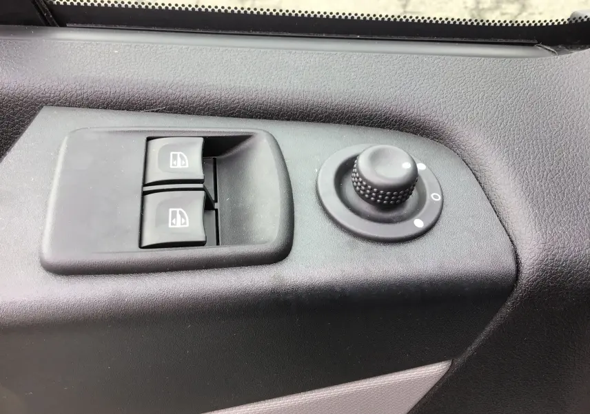Gros plan sur les commandes de lève-vitres et réglage des rétroviseurs côté conducteur du Renault Trafic Planche Cabine blanc 2019.