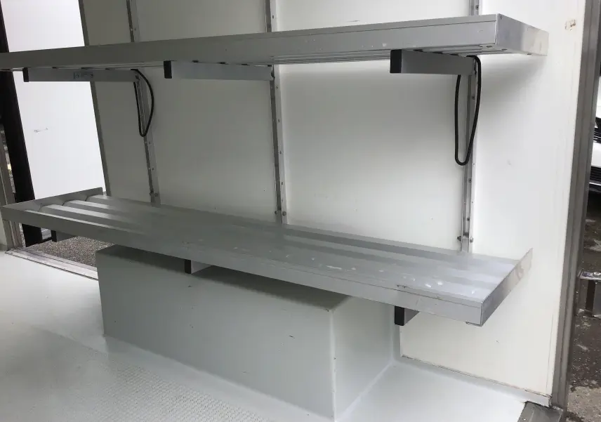 Intérieur blanc du Renault Trafic Plancher Cabine 2019 avec étagères métalliques dans la caisse frigorifique.