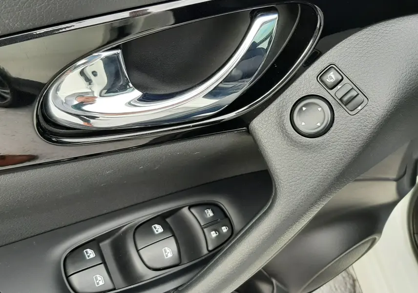 Poignée de porte intérieure côté conducteur du Nissan Qashqai blanc 2020 avec commandes des vitres et réglages des rétroviseurs.