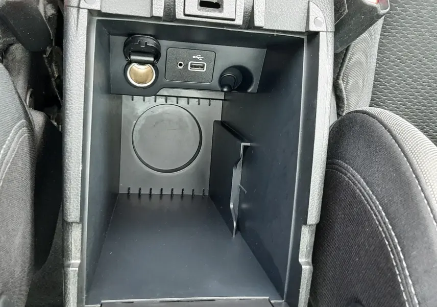Gros plan sur la console centrale ouverte du Nissan Qashqai blanc, montrant prise USB et allume-cigare.