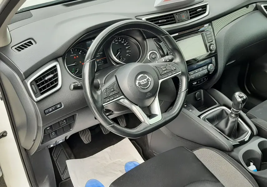 Intérieur du Nissan Qashqai blanc 2020, vue côté conducteur, volant multifonction et boîte manuelle visibles.