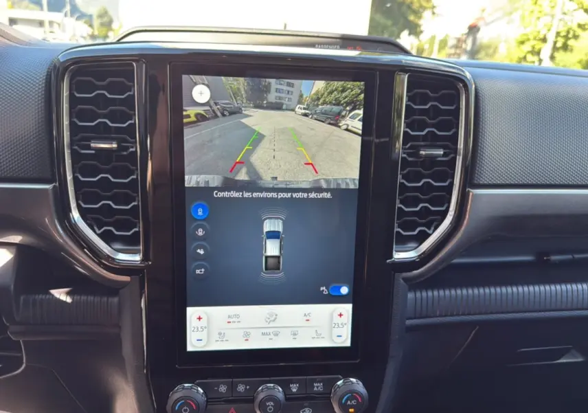 Vue intérieure centrée sur l’écran tactile vertical du Ford Ranger blanc glacier, affichant la caméra de recul et les commandes climatisation.